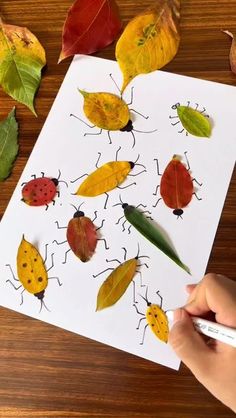 a person is drawing on paper with leaves and ladybugs in the fall colors