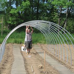 a man standing in the middle of a garden holding his hands up above his head