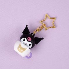 a black and white cat holding a baby bottle keychain on a purple background