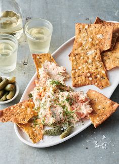 an appetizer plate with crackers, pickles and olives on the side