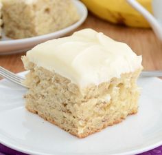 a close up of a piece of cake on a plate with bananas in the background