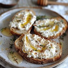 three pieces of bread with cream cheese and herbs on them sitting on a white plate