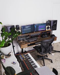 there is a desk with many electronic devices on it and a potted plant in the corner