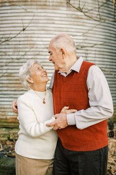 an older man and woman standing next to each other in front of a metal building