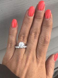 a woman's hand with an orange manicured nail polish holding a diamond ring