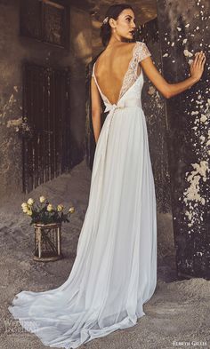 a woman in a white dress standing next to a wall