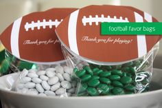 two football treat bags in a bowl filled with green and white candies, candy