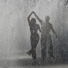 two people are standing in the rain with their hands up to their heads and arms