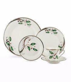 a white and green christmas dinnerware set with holly designs on it, including saucer