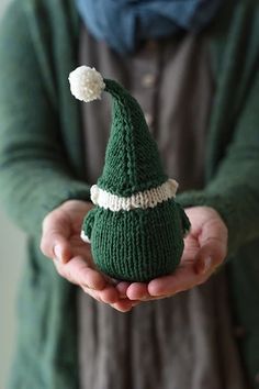 a person holding a knitted christmas hat in their hands