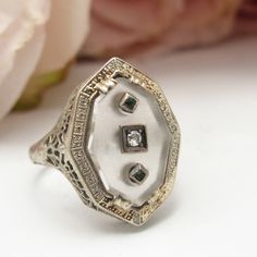 This Beautiful Art Deco Came Out Of A Well-Known Antique Jewelry Dealer's Private Collection. Finely Detailed Vintage Art Deco Rock Crystal, Diamond And Emerald Ring (Circa 1920s To 1930s) Crafted In 10k White Gold With A Filigree Setting. The Fanciful Ring Has A Small Center Diamond With Two Flanking Emeralds Set In Frosted Rock Crystal. The Face Of The Ring Measures Approx. 13.50 Mm By 8.96 Mm. Ring Is A Us Size 5.5 And Is Sizeable. It Weighs 2.88 Grams And Is In Excellent Condition. A Really Special Old Ring! Our Rings Come Ready For Gift-Giving With Velvet Presentation Boxes. Box In Photos For Display Purposes. White 14k Gold Jewelry With Single Cut Diamonds, Art Deco White Jewelry With Rose Cut Diamonds, White Art Deco Jewelry With Rose Cut Diamonds, Victorian White Diamond Jewelry, Victorian White Jewelry With Diamond Accents, Heirloom White Diamond Cut Jewelry, Victorian White Platinum Jewelry, Antique White Diamond Cut Jewelry, White Sterling Silver Art Deco Jewelry