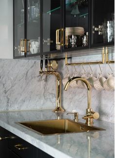 a kitchen with marble counter tops and gold faucets on the wall above the sink