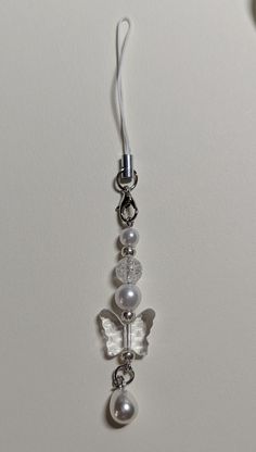 a pair of earrings hanging from a hook on a white wall with pearls and beads