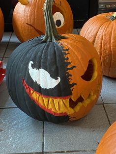 several pumpkins with faces painted on them sitting on the floor next to each other