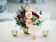 an arrangement of flowers and greenery on a table with a note attached to it