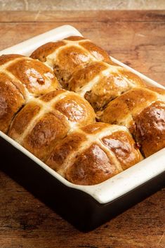 hot cross buns in a baking dish on a wooden table