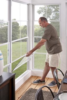 an older man is cleaning the windows in his home