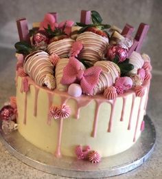 a cake with pink icing and chocolate covered strawberries