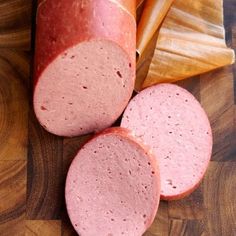 three slices of sausage on a wooden cutting board