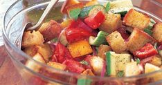 a glass bowl filled with chopped vegetables on top of a wooden table