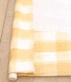 a yellow and white checkered blanket laying on top of a wooden floor