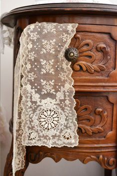 an old wooden cabinet with lace on it