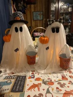 three halloween decorations on a table with ghost hats and buckets in front of them