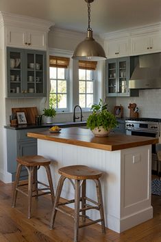 a kitchen with two stools in front of an island