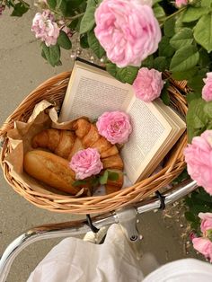 a basket filled with pastries and flowers next to a book on top of a table