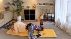 a woman is doing yoga on a mat in the living room with her feet up