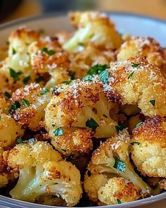 a white bowl filled with cooked cauliflower covered in parmesan cheese and herbs