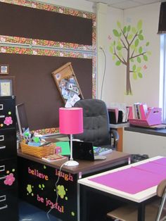 an office with desks, filing cabinets and a tree painted on the wall behind it