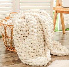 a white blanket sitting on top of a wooden floor next to a basket filled with blankets