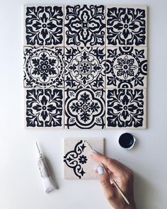 a person is painting some black and white tiles on the wall with paintbrushes