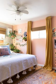 a bedroom with pink walls and gold drapes on the windowsill, an area rug in front of a bed