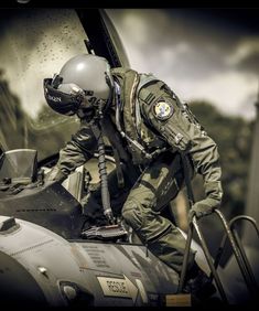 a man in an air force pilot's uniform sitting on top of a helicopter