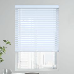 a living room with white walls and windows covered in blinds that have horizontal shades on them