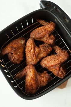 chicken wings cooking on the grill in an electric air fryer, ready to be cooked