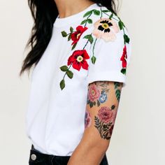 a woman with tattoos on her arm wearing a white t - shirt and black jeans