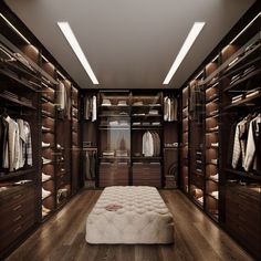 a large walk in closet with lots of clothes on the shelves and drawers, along with a footstool