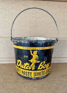 an old metal bucket sitting on top of a wooden table next to a white wall