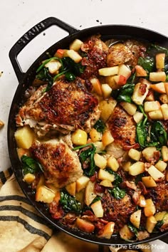 a skillet filled with meat, potatoes and spinach