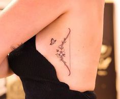 a woman with a tattoo on her back holding a flower and butterfly in one arm