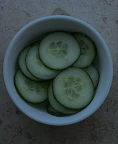 a white bowl filled with cucumbers on top of a table