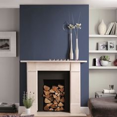 a living room filled with furniture and a fire place in front of a blue wall