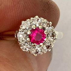 Beautiful vintage cluster ring with pink ruby and spinel, on a 9ct yellow gold shank, and platinum shoulders. This ring has a very vibrant pink centre stone which tests as ruby but may be a man-made ruby, and is surrounded by very sparkly white spinel. Condition: Excellent  Head size: 10mm x 10mm Finger size: Select from drop down menu. There is only one of these rings and it's existing size is N 1/2 ( US finger size 7) There is only one of these rings. This ring has a 9ct gold hallmark on it wi Classic Ruby Cluster Ring With Center Stone, Classic Cluster Ruby Ring With Center Stone, Red Ruby Cluster Ring With Rose Cut Diamonds, Classic Cluster Ruby Ring, Ruby Cluster Diamond Ring, Red Cluster Ring With Rose Cut Diamonds, Red Diamond Cluster Ring With Halo Setting, Cluster Ruby Ring With Center Stone, Ruby Cluster Ring For Promise Occasion