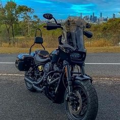 the motorcycle is parked on the side of the road in front of the cityscape