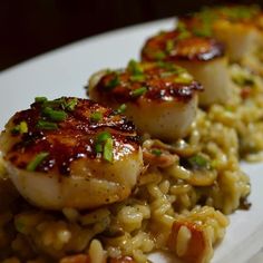 two scallops are on top of rice and garnished with green onions