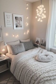 a white bed sitting in a bedroom next to a window with lights on the wall