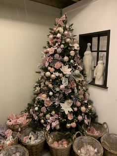 a small christmas tree with pink and white ornaments in baskets on the floor next to it